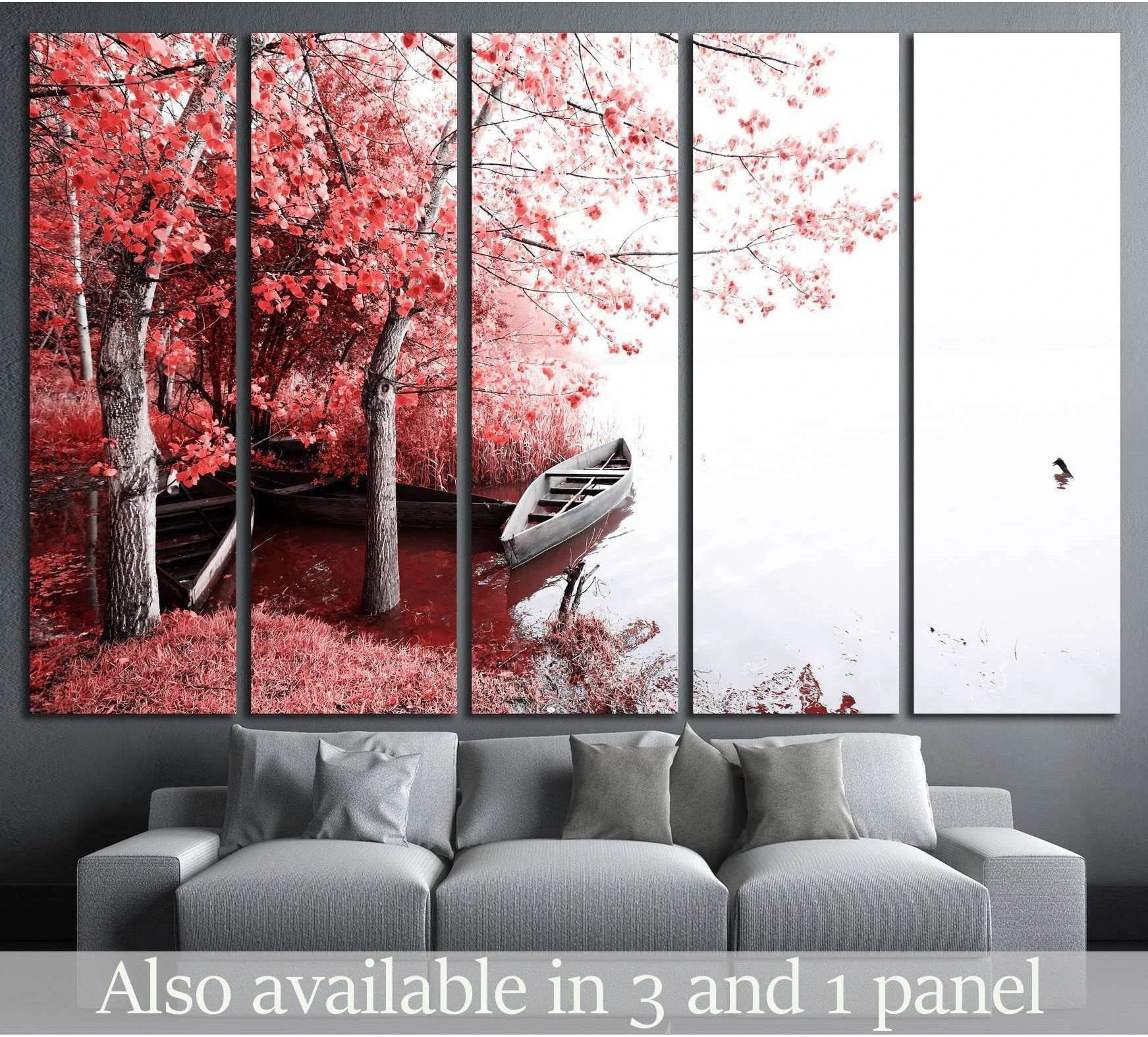 Red boat canvas print beside pink lakeside trees with reflective water, hung above a gray sofa