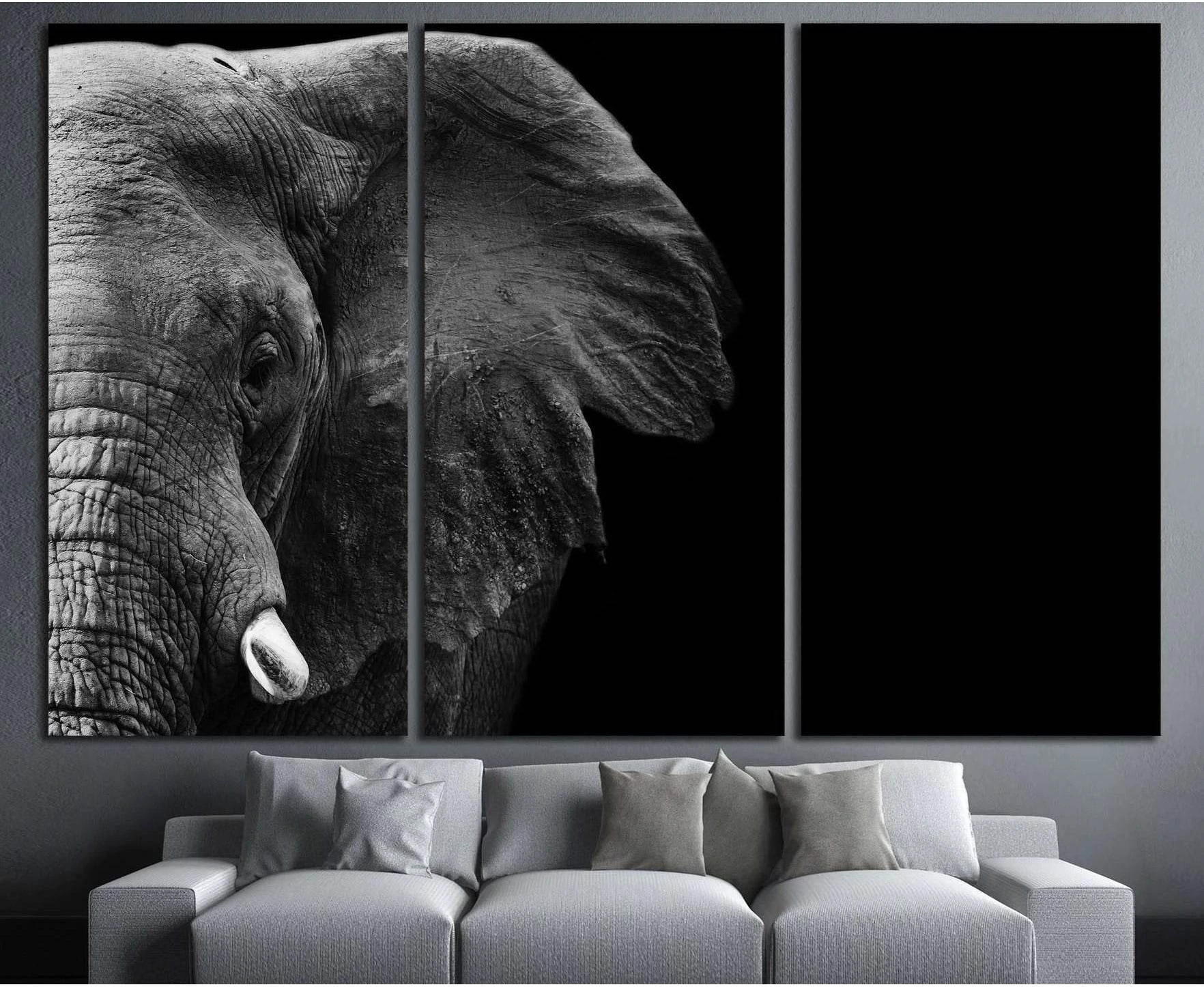 Black and white elephant triptych canvas print above a sofa in a modern living room