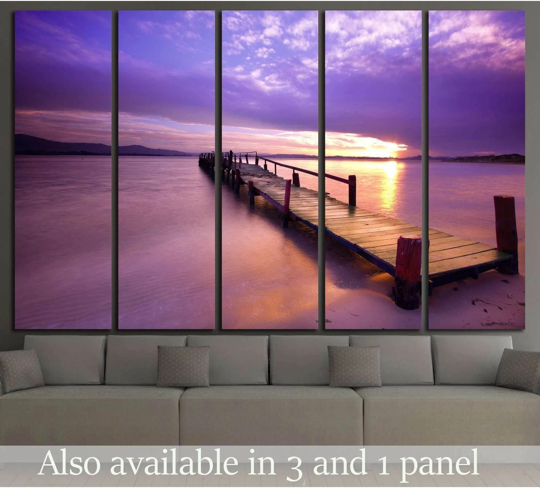 Purple sunset pier canvas print above sofa in modern living room with glowing water reflections