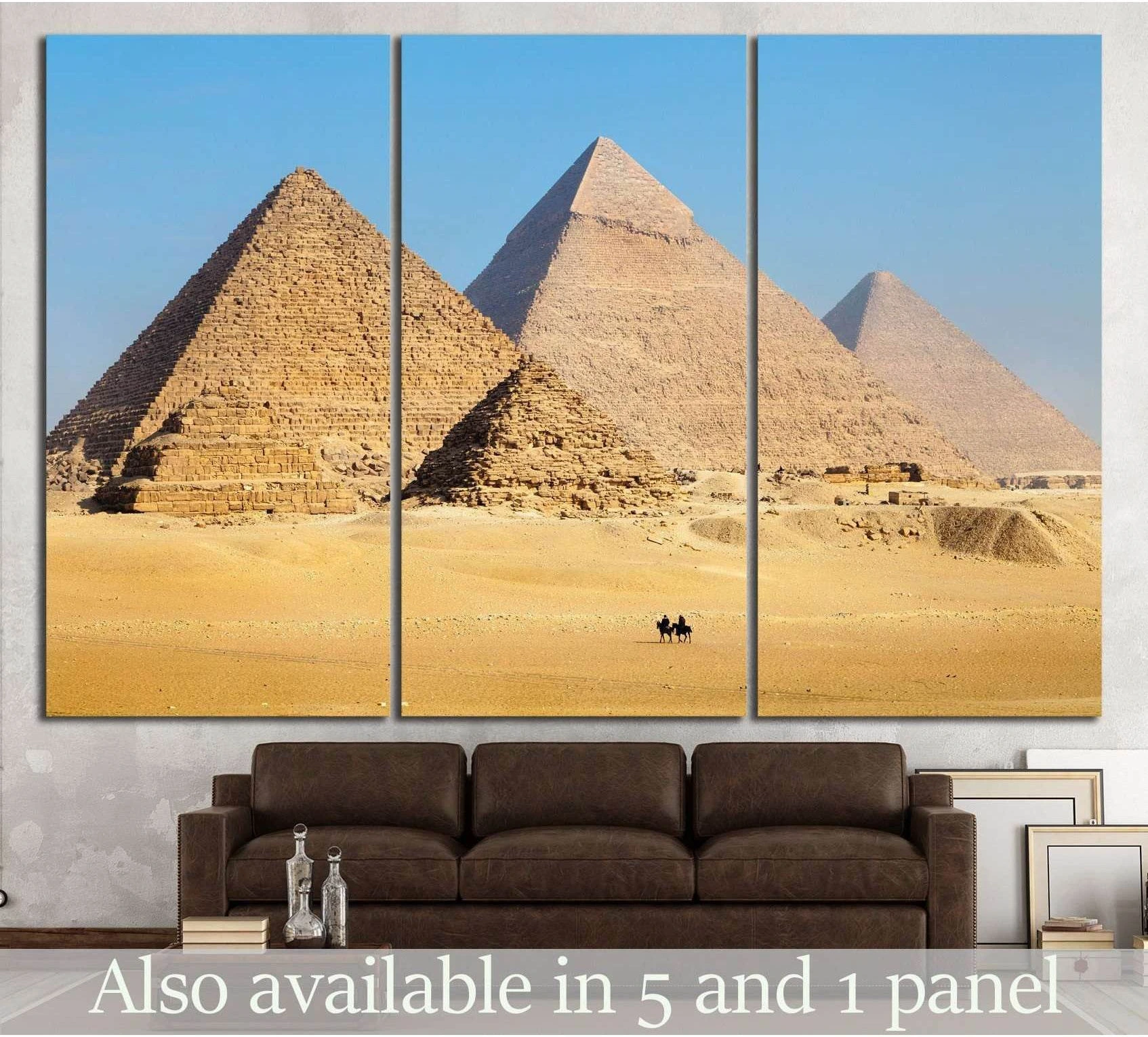 Giza pyramids canvas print with desert sand, blue sky, and camel riders above a sofa