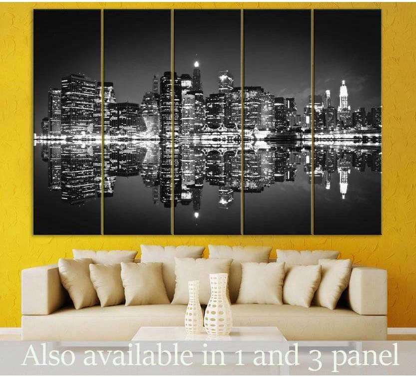 Black and white NYC skyline canvas print with mirrored reflection, displayed as five panels above a sofa in a modern living room