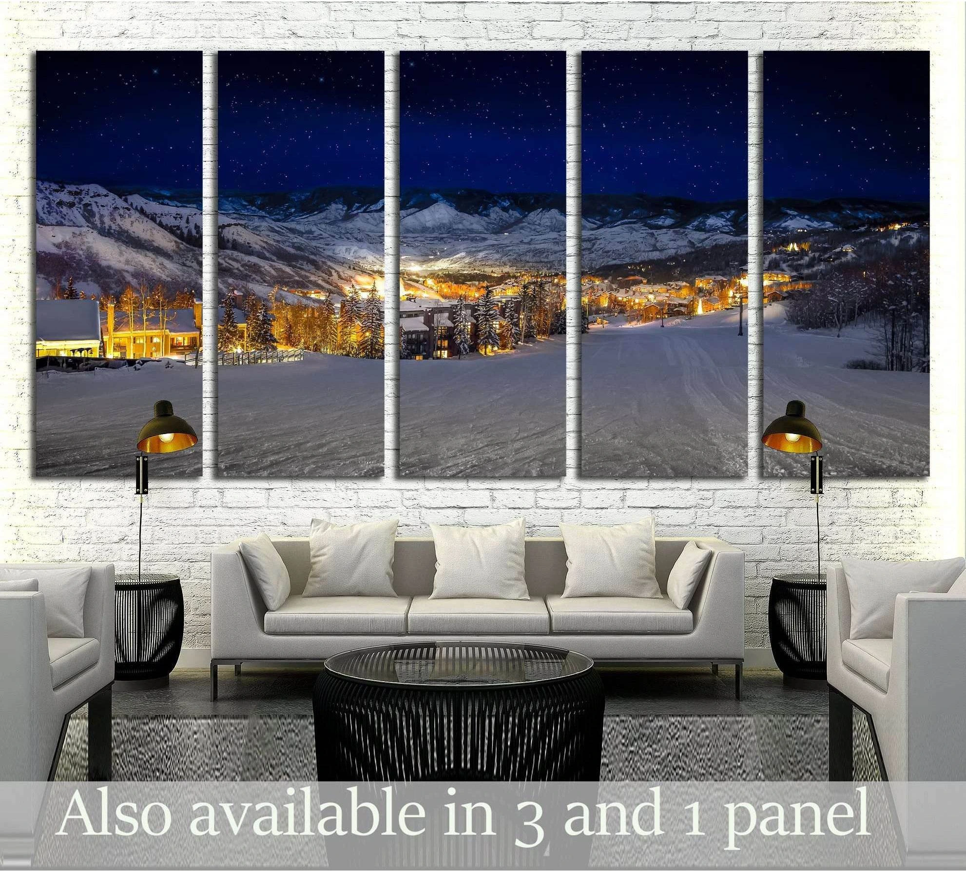 Snowy alpine village and mountains at night canvas print above a sofa in a modern living room