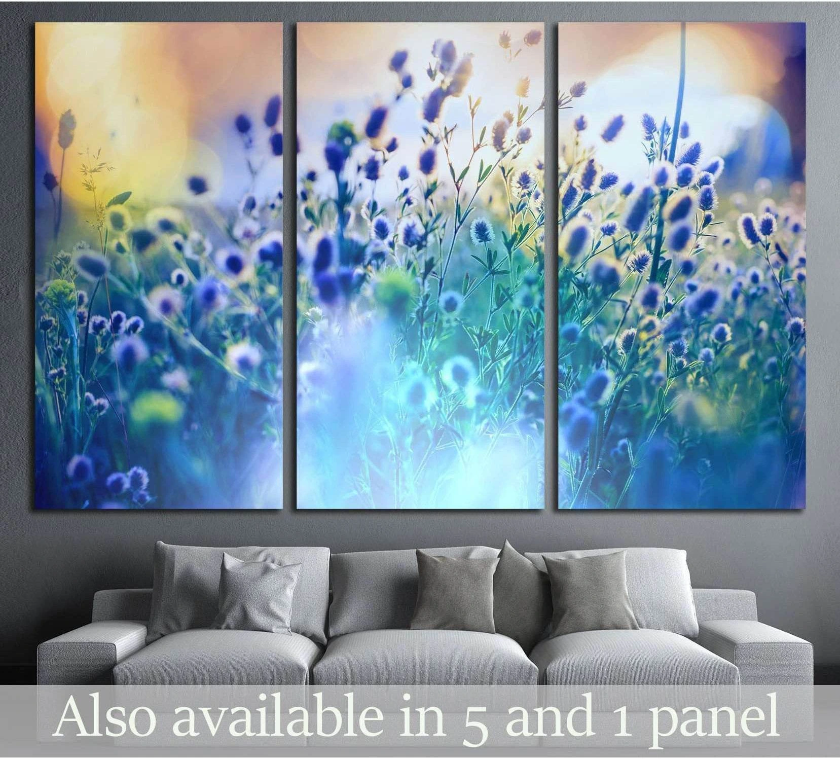 Blue wildflower meadow canvas print in a three-panel layout above a grey sofa in a modern living room