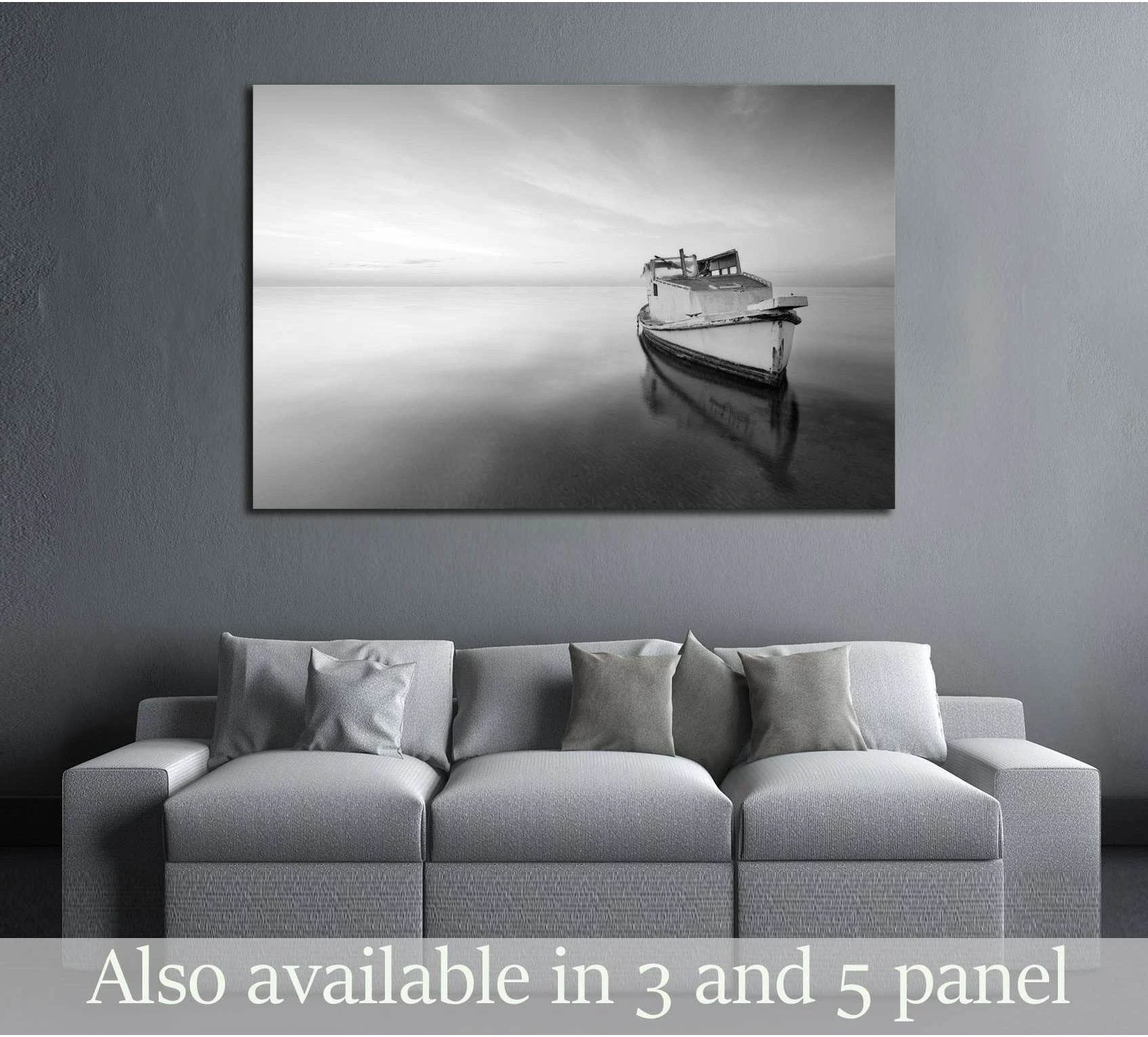 Black and white abandoned boat canvas print hung above a sofa in a modern gray living room
