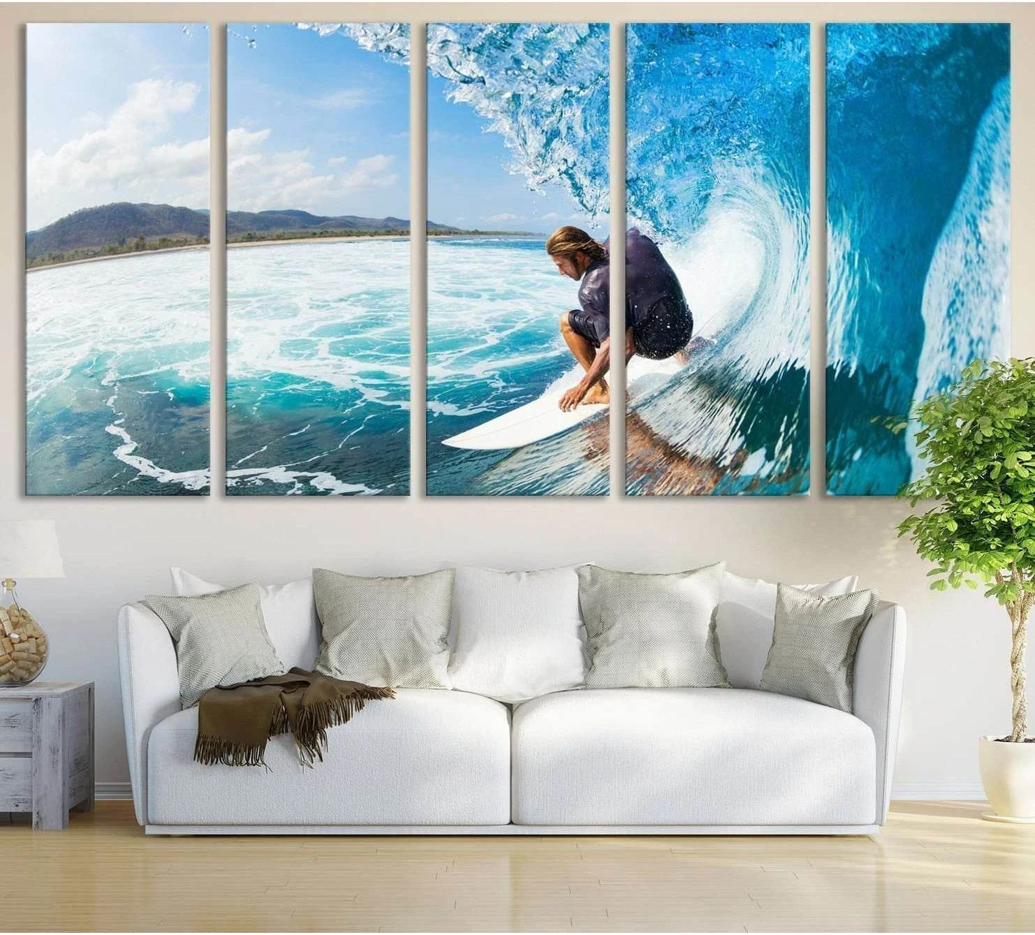 Surfer riding inside a curling blue wave multi-panel canvas print displayed above a white sofa in a coastal living room