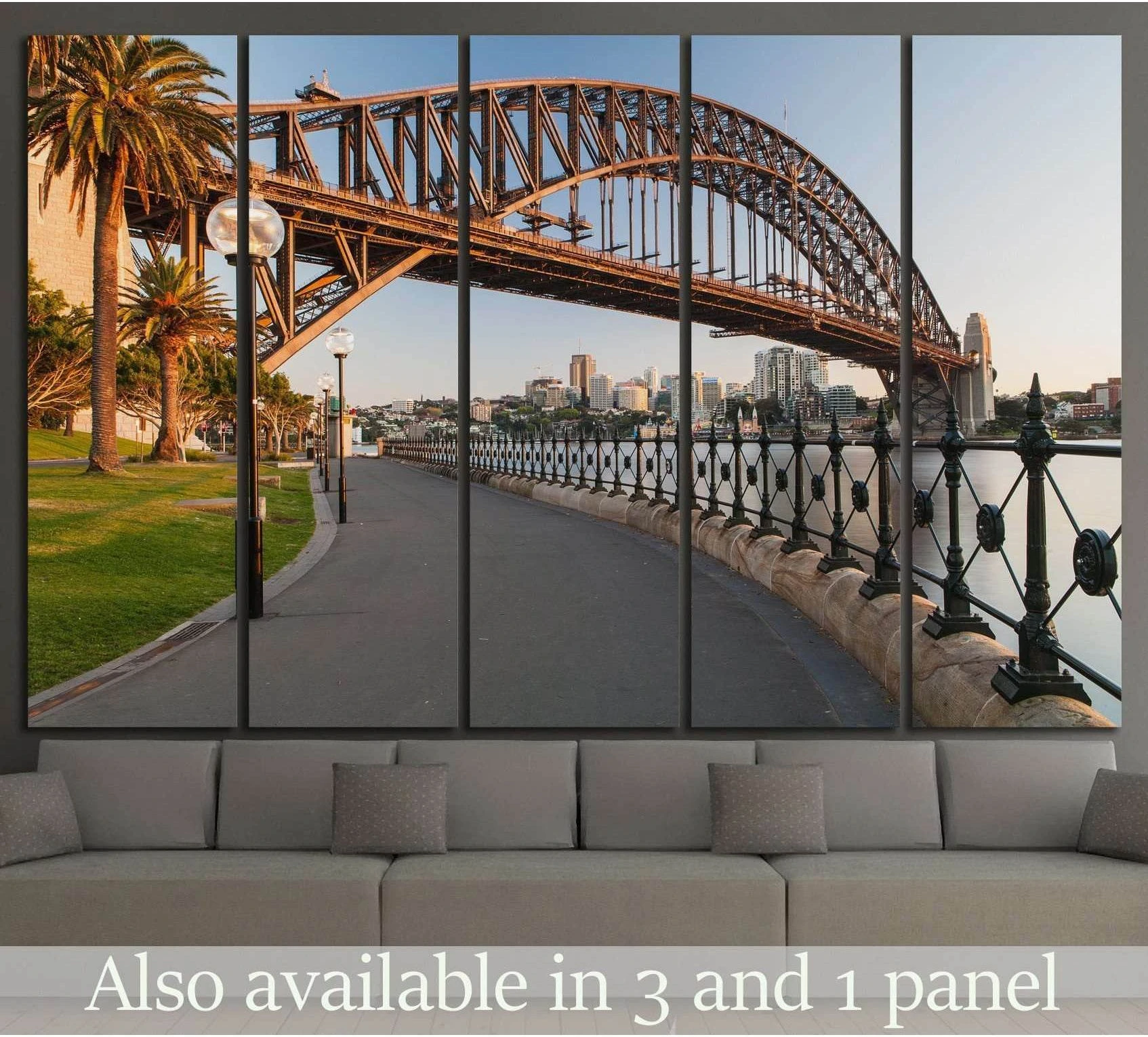 Sydney Harbour Bridge canvas print above sofa with waterfront path, palm trees, and warm city skyline