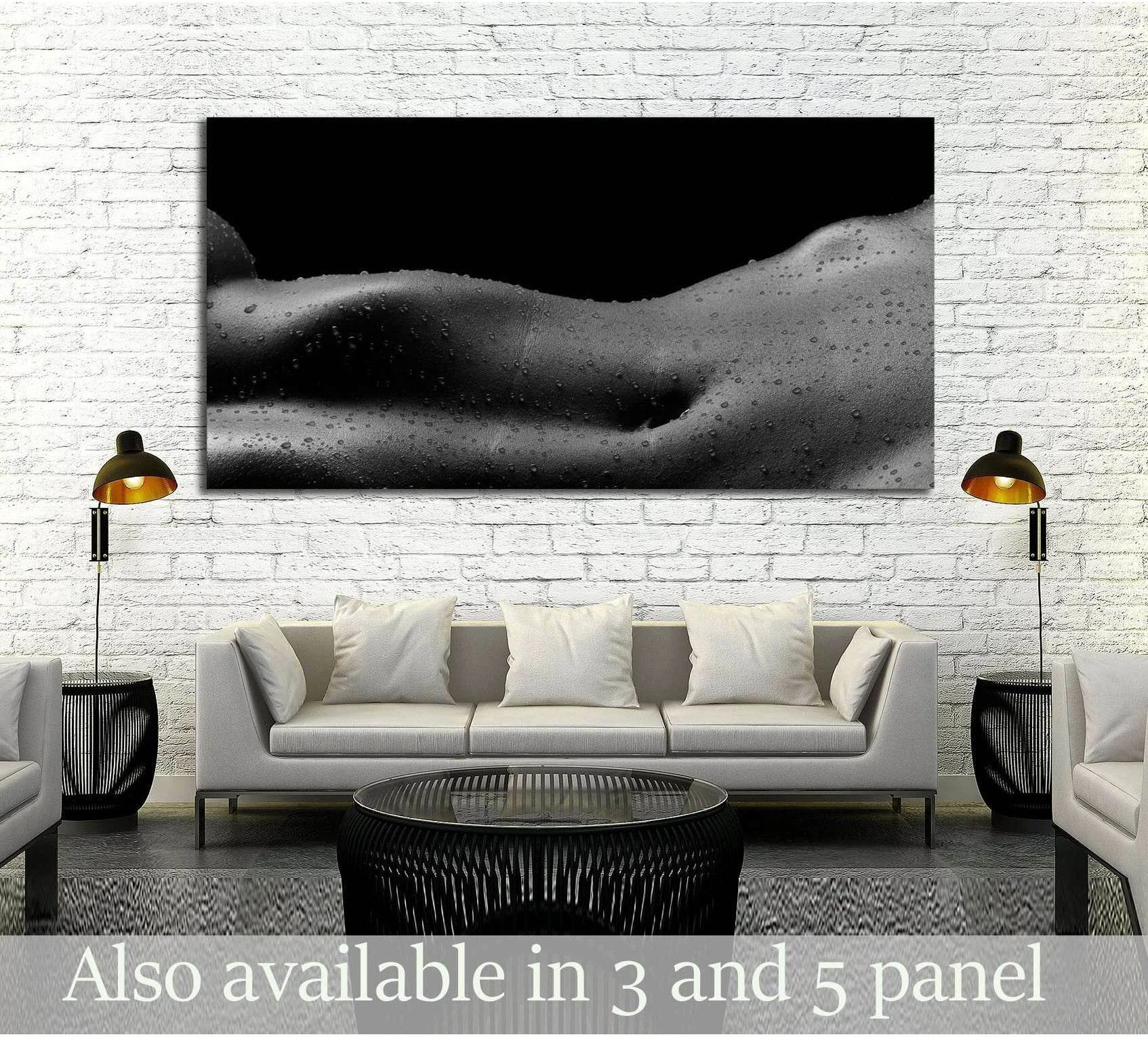 Black and white nude torso canvas print with water droplets displayed above a sofa in a modern living room