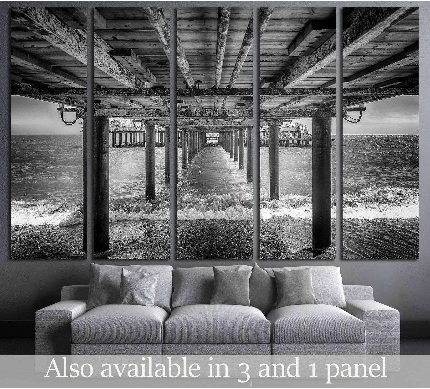A black and white photograph of the underside of a pier with a rest area at the end