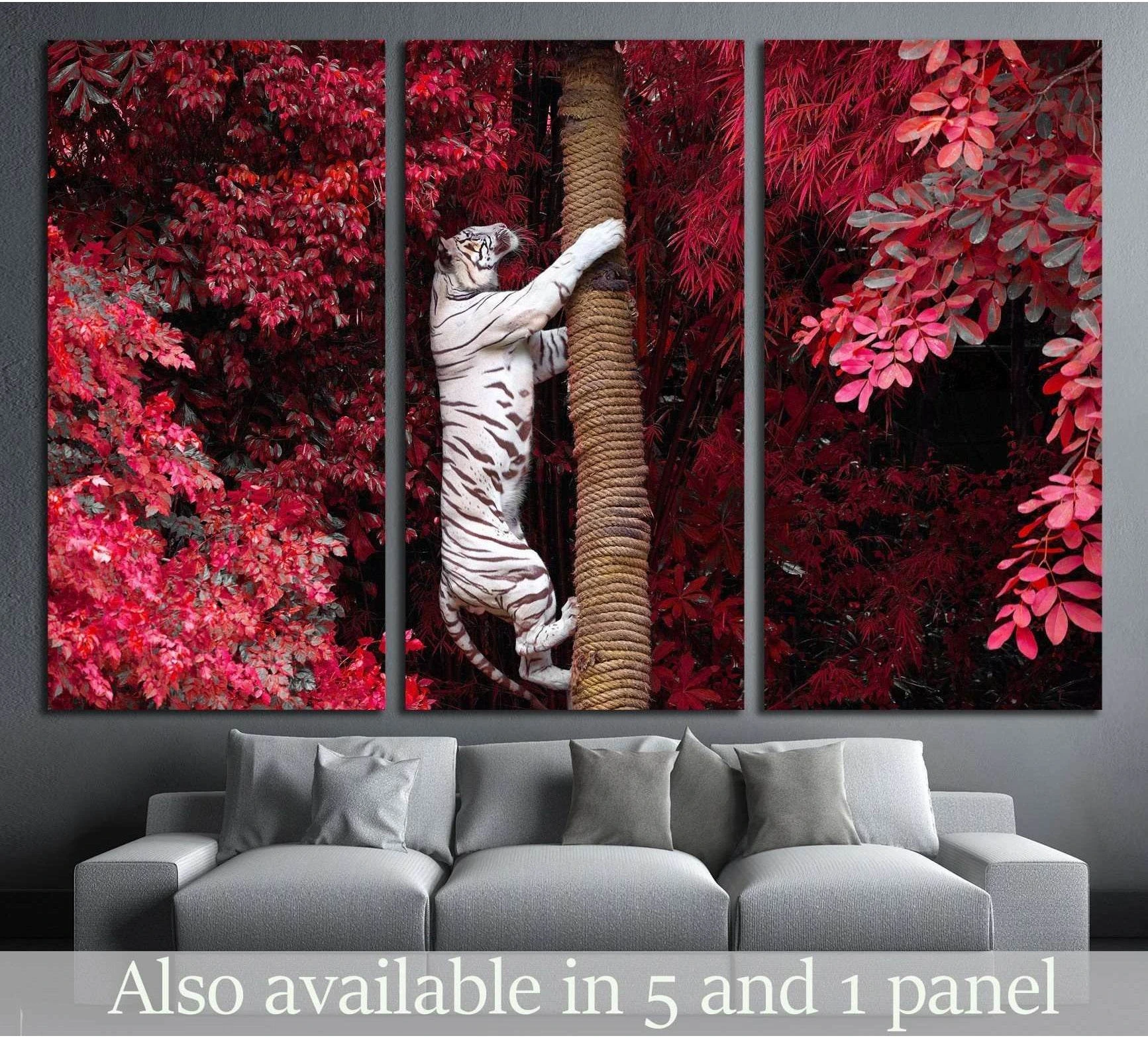 White tiger canvas print climbing a tree among red foliage, displayed above a gray sofa