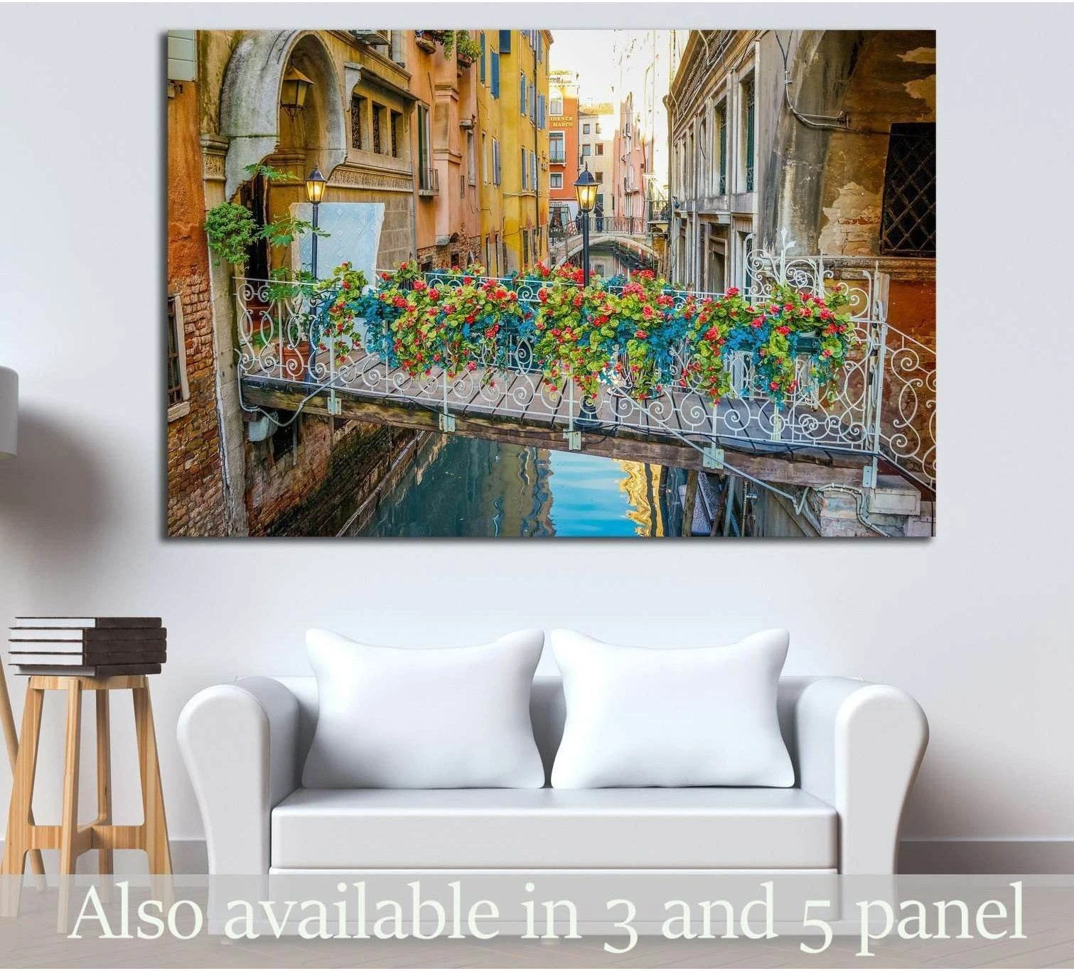 Venice canal bridge canvas print with colorful flower boxes above blue water, displayed over a white sofa