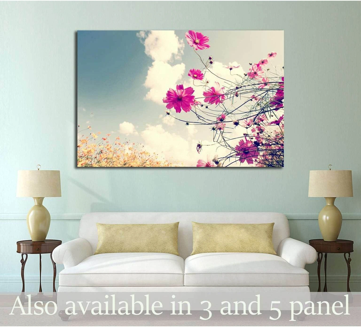 Pink cosmos flowers canvas print with soft blue sky and clouds, hung above a sofa in a pastel living room