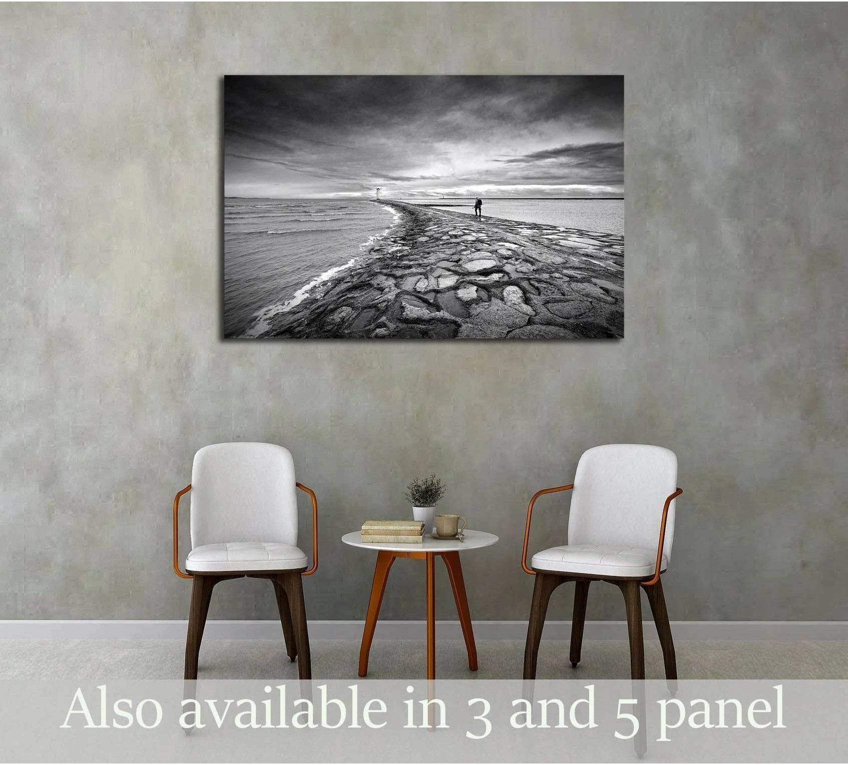 Black and white jetty canvas print with lone figure on a winding sea wall above chairs in a modern room
