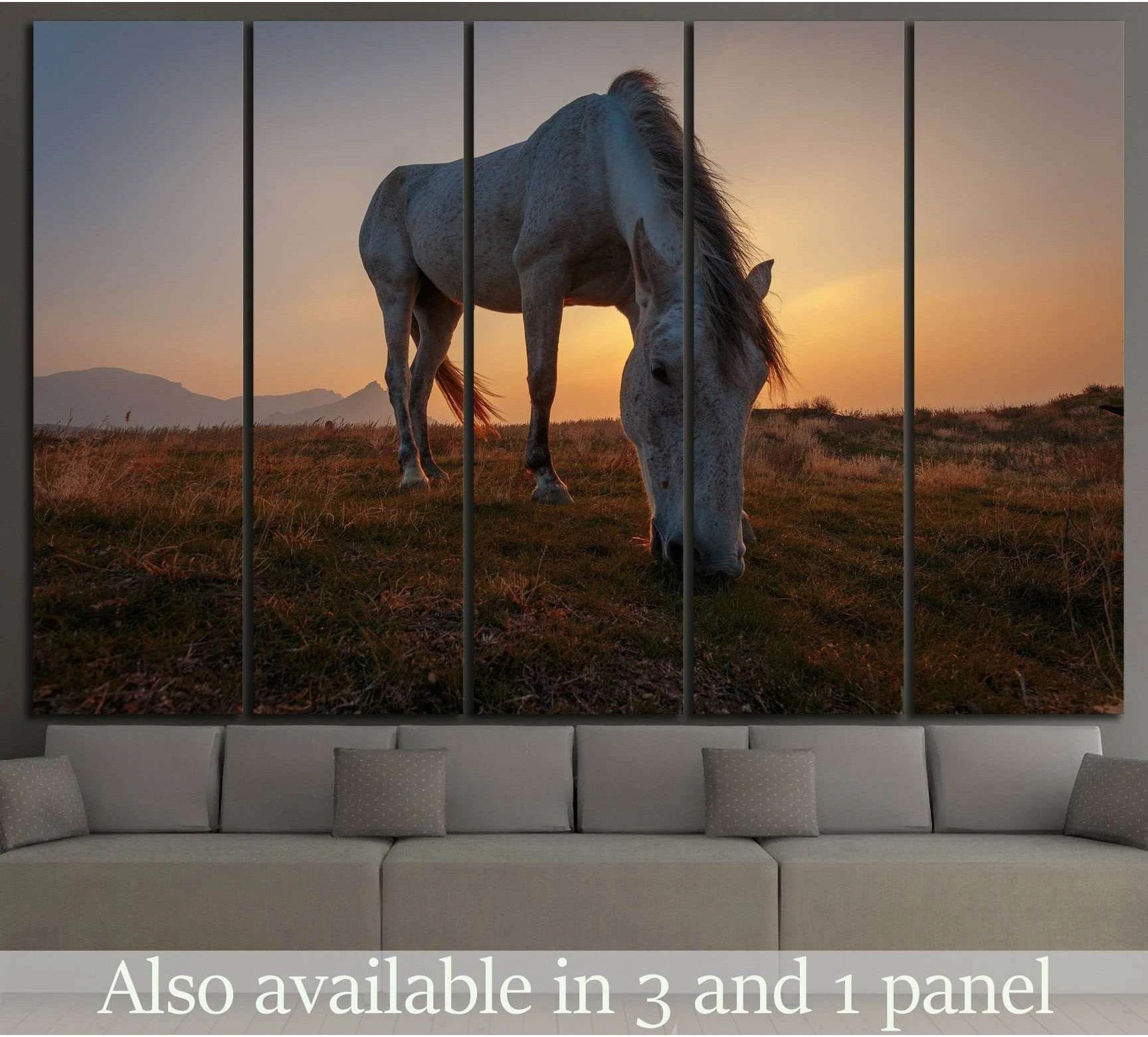 White horse canvas print of a grazing horse at sunset above a sofa in a warm neutral living room
