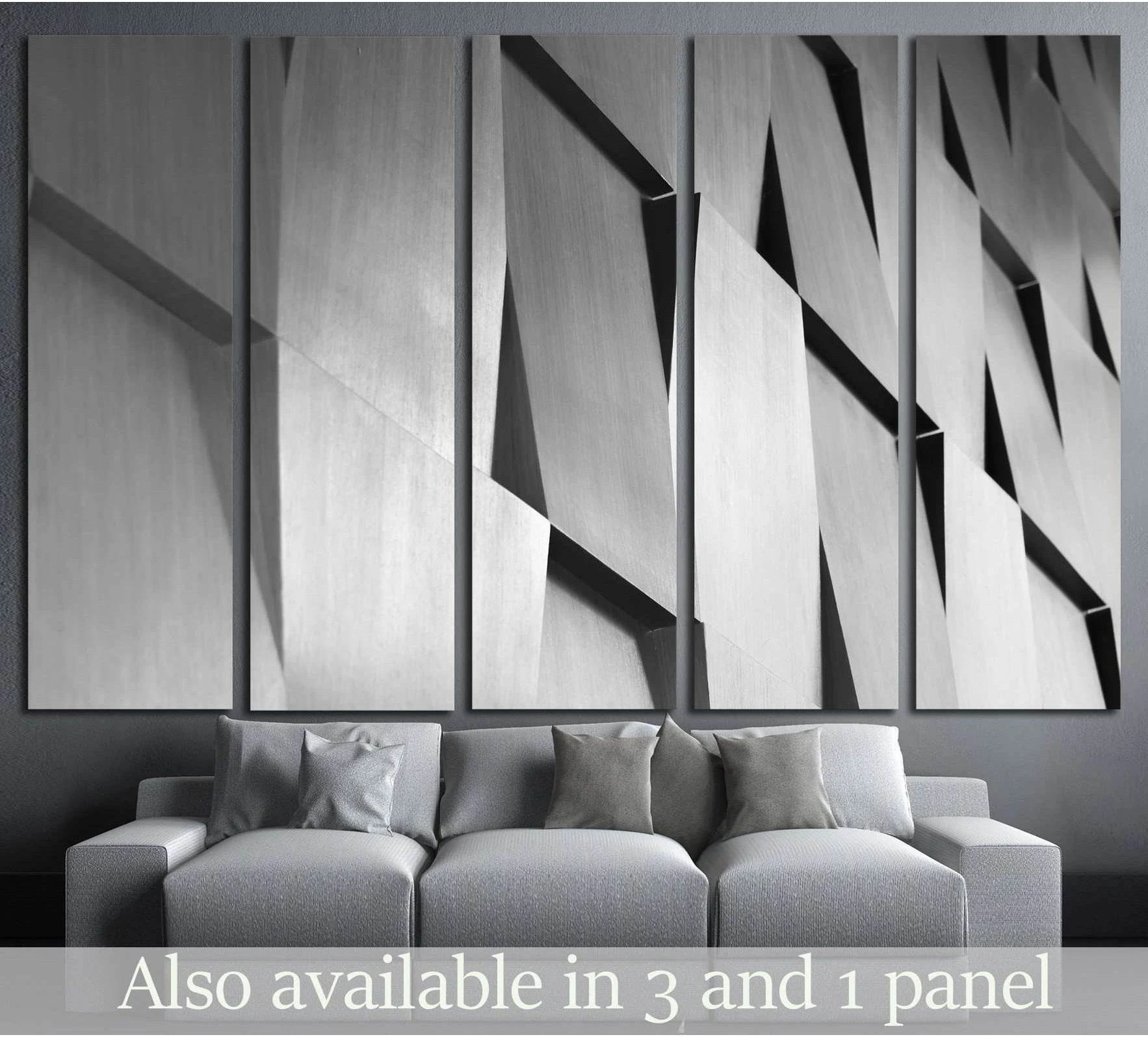 Monochrome geometric wood canvas print with layered angular panels above a grey sofa in a modern living room